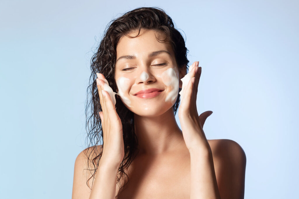 Lächelnde junge Frau waschen Schaum Gesicht von natürlichen schaumigen Gesichtsgel, Reinigung der Haut