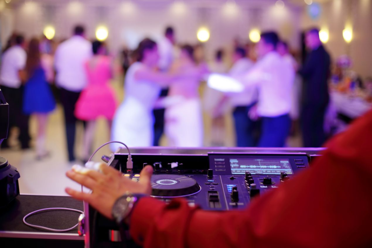 Hochzeits DJ Brandenburg am Mischpult mit tanzenden Gästen im Hintergrund – perfekte Musik für eine unvergessliche Feier.
