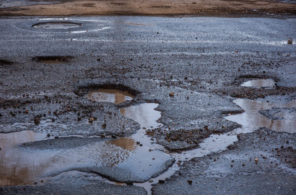 Straßenoberfläche mit Schlaglöchern nach Regen | Kaltasphalt