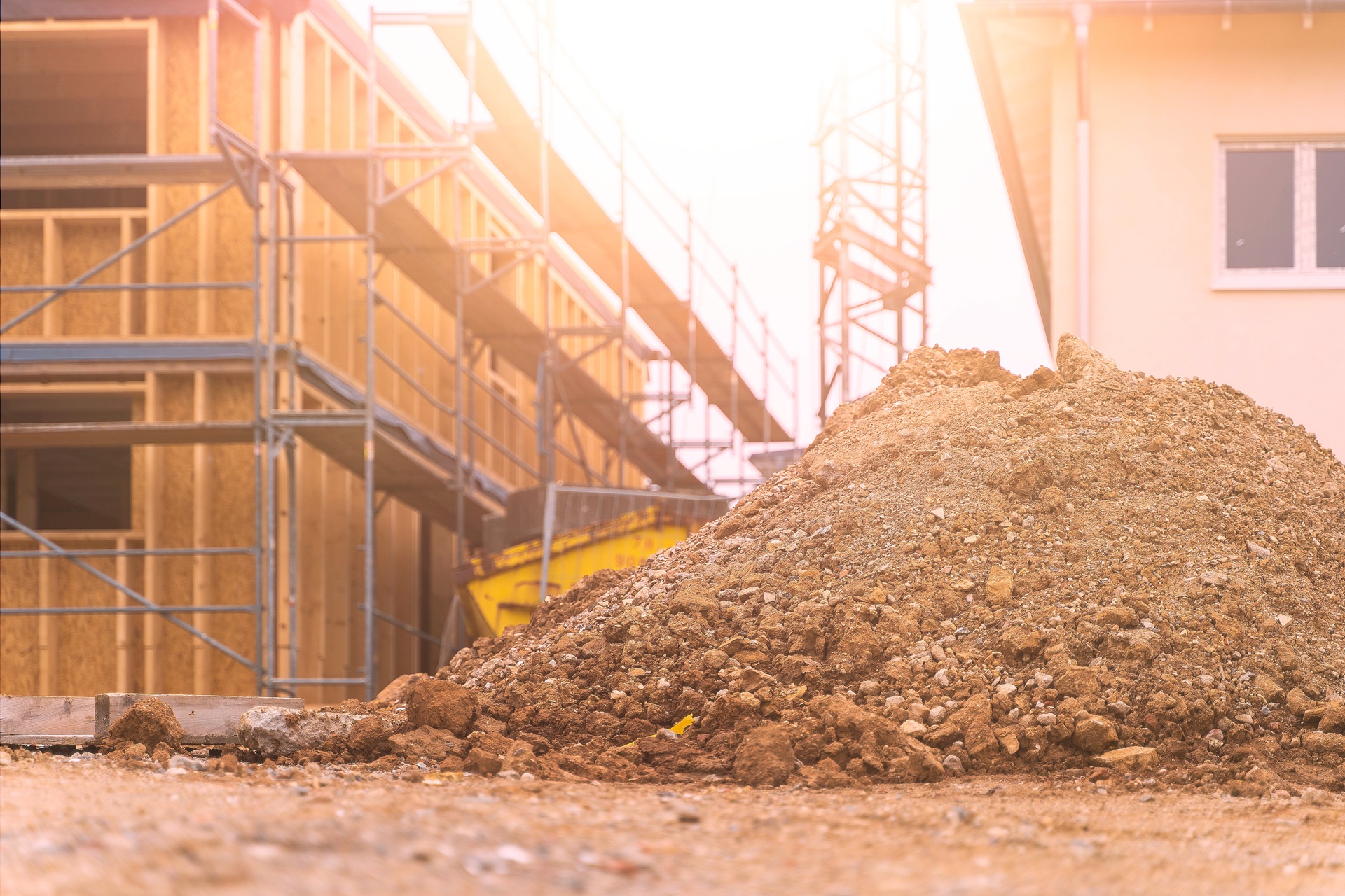 Großer Erdhaufen vor im Bau befindlichem Haus | Baustellenzaun